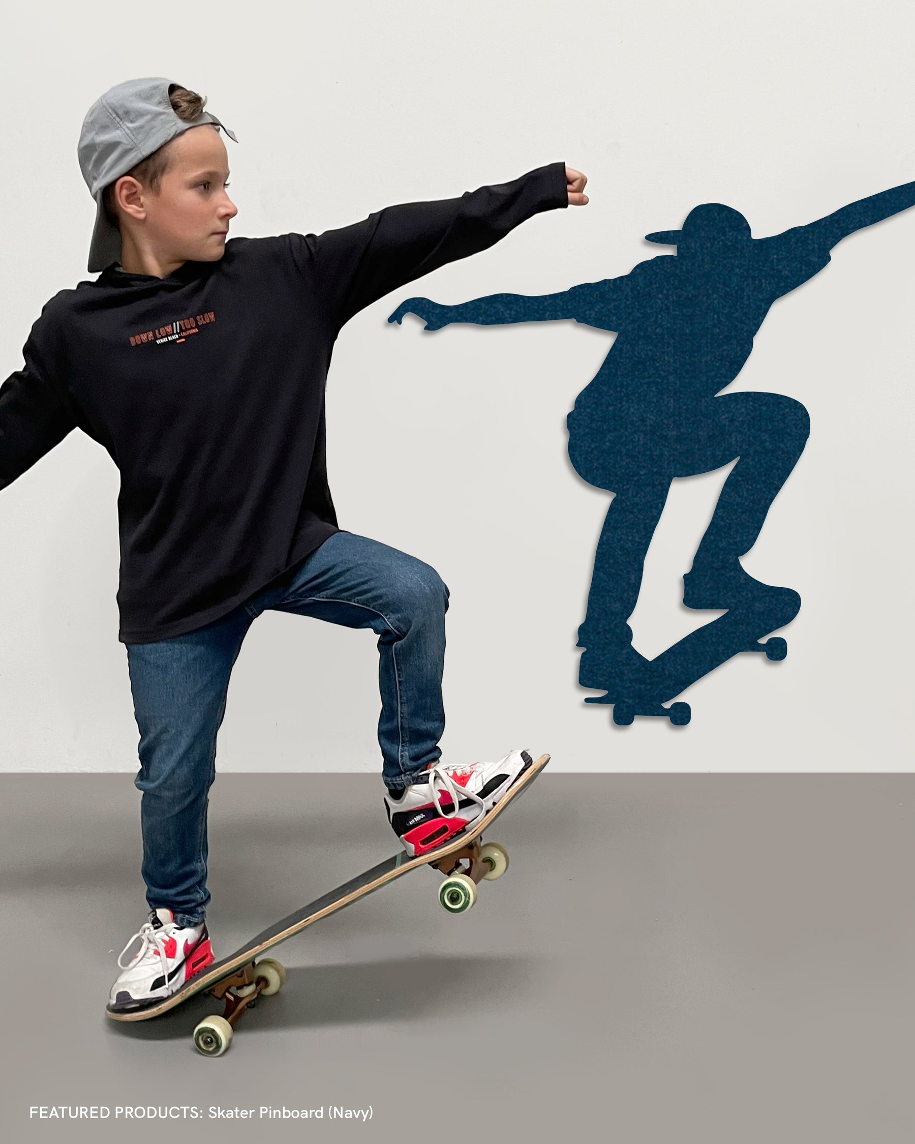 Child with skateboard next to a Skater Pin Board, showcasing a fun and sporty way to organize notes and memories.