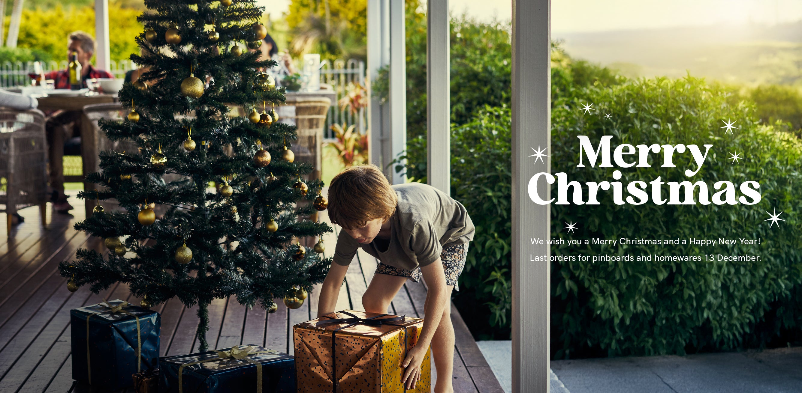 Merry Christmas from the team at Lilly & Lolly, kids designer furniture. Image shows a child getting a gift from under the Christmas tree.