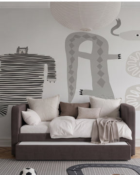 A modern children's daybed in dark brown fabric with white and beige bedding, styled in a minimalist room with a large grey animal mural on the wall and a white paper lantern hanging above. Daybed can be a bed by night, lounge by day and has an extra pull out bed for guests.
